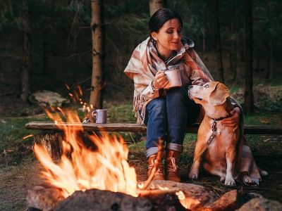 woman and dog sitting near camp fire